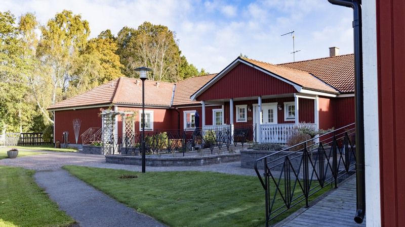 Stenlagd trädgård framför rött trähus