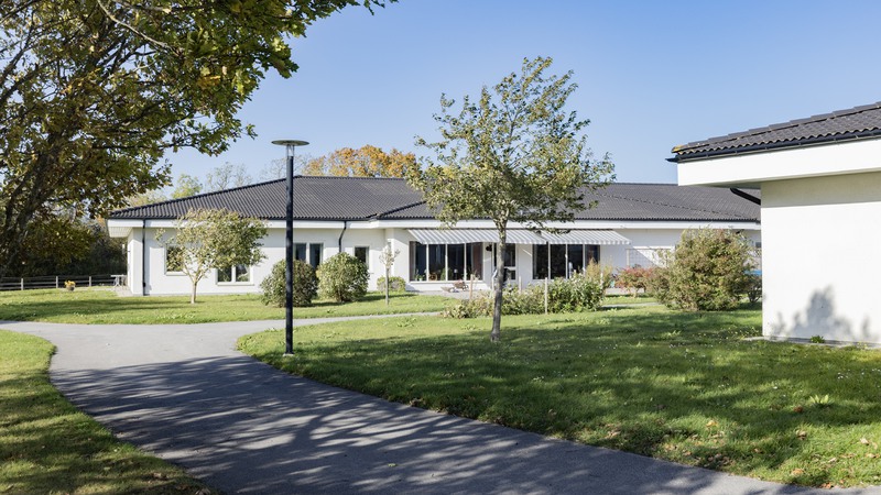 Trädgård och större vit byggnad