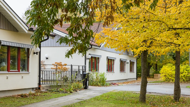 Ett vitt hus med röda fönster och ett svart staket.
